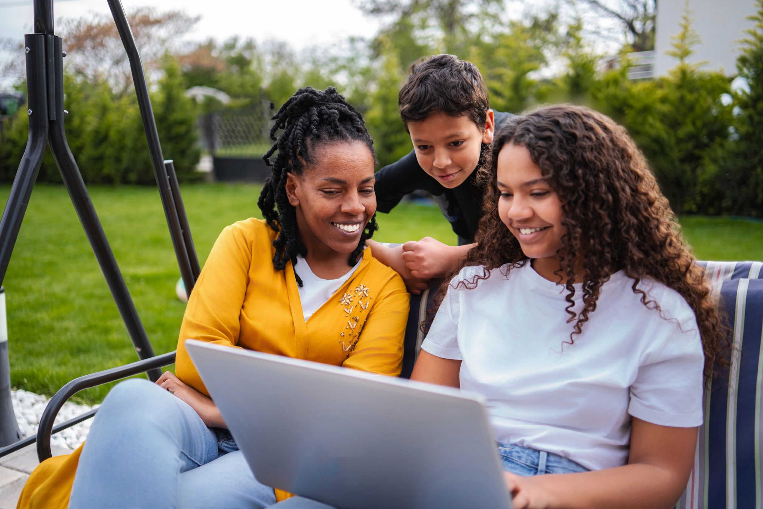 Family spending time together outdoors with a laptop